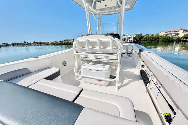 Slide: The Image of 2021 Robalo R242 Explorer boat interior with seating and storage, docked on calm water. - 11