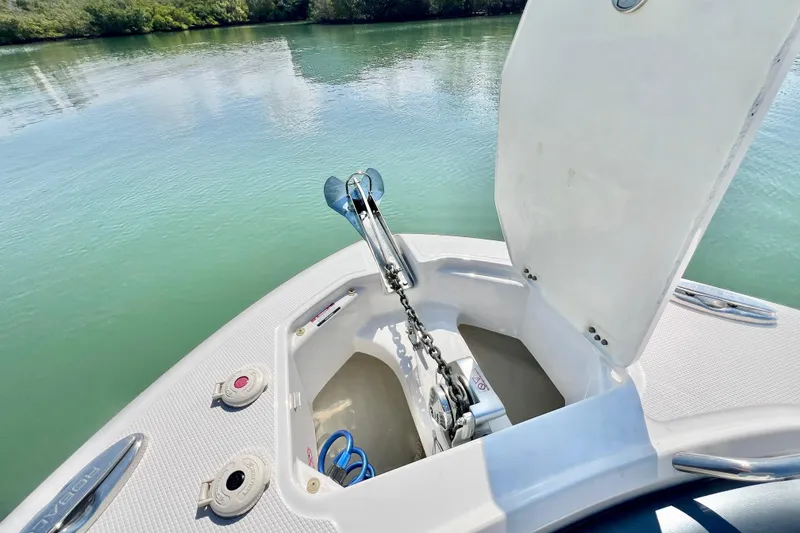 Slide: The Image of 2021 Robalo R242 Explorer boat anchor compartment open on calm water. - 26