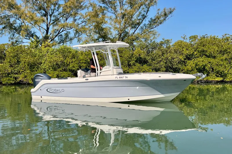 Slide: The Image of 2021 Robalo R242 Explorer boat on calm water, surrounded by lush greenery. - 5