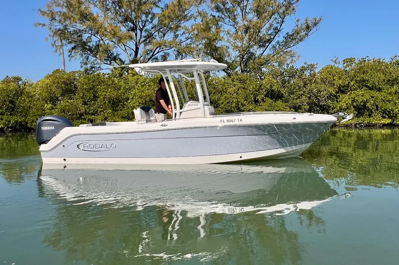 Slide: The Image of 2021 Robalo R242 Explorer boat on calm water, surrounded by lush greenery. - 6