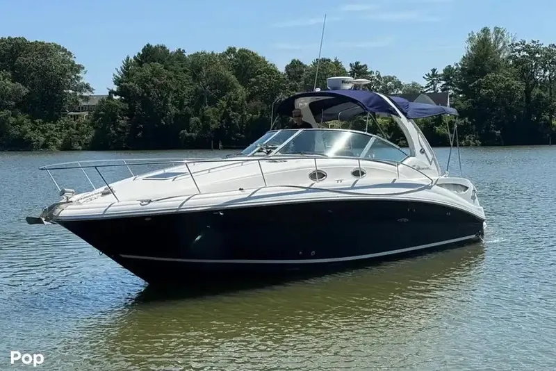 Slide: The Image of 2006 Sea Ray Sundancer 320 yacht on calm water, featuring sleek design and blue canopy. - 2