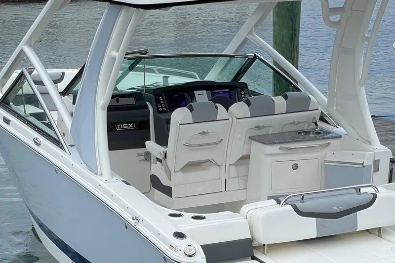 Slide: The Image of 2024 Chaparral 280 OSX boat interior with helm, seating, and kitchenette by the water. - 1