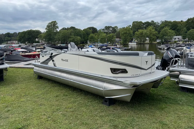 The Image of 2026 Tahoe Pontoon LTZ Quad Lounger 23 on grassy shore near marina. - 0
