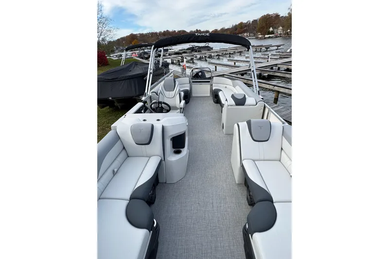 Slide: The Image of 2026 Tahoe Pontoon LTZ Quad Lounger 23 with spacious seating, docked by a scenic lake. - 11