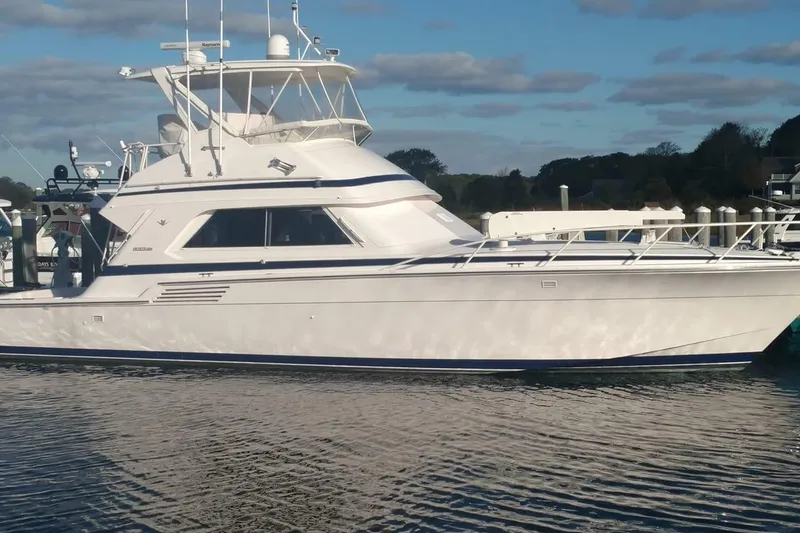 The Image of 1996 Bertram 46 Convertible yacht docked on calm water under a blue sky. - 0