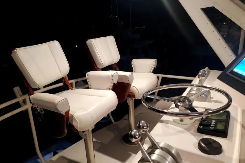 Slide: The Image of Interior of a 1996 Bertram 46 Convertible yacht with white captain's chairs and steering wheel. - 26