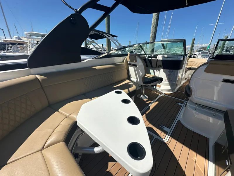 Slide: The Image of 2019 Sea Ray SLX 280 interior with tan seating, white table, and wood flooring. - 10