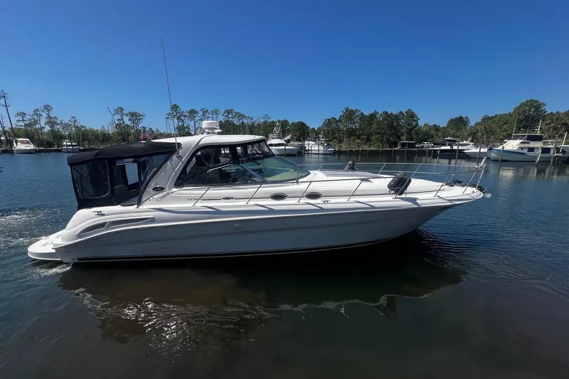 The Image of 2003 Sea Ray 410 Express Cruiser on calm water, surrounded by trees and other boats. - 0