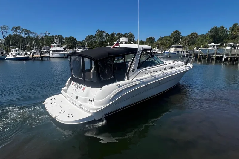 Slide: The Image of 2003 Sea Ray 410 Express Cruiser in marina, featuring sleek design and black canopy. - 3