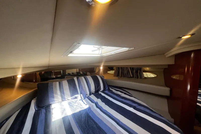 Slide: The Image of Cozy cabin interior of 2003 Sea Ray 410 Express Cruiser with striped bedding and natural light. - 40