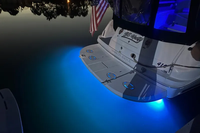 Slide: The Image of 2003 Sea Ray 410 Express Cruiser with blue underwater lights at night. - 49