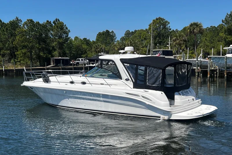 Slide: The Image of 2003 Sea Ray 410 Express Cruiser on calm water, surrounded by lush greenery and docks. - 7
