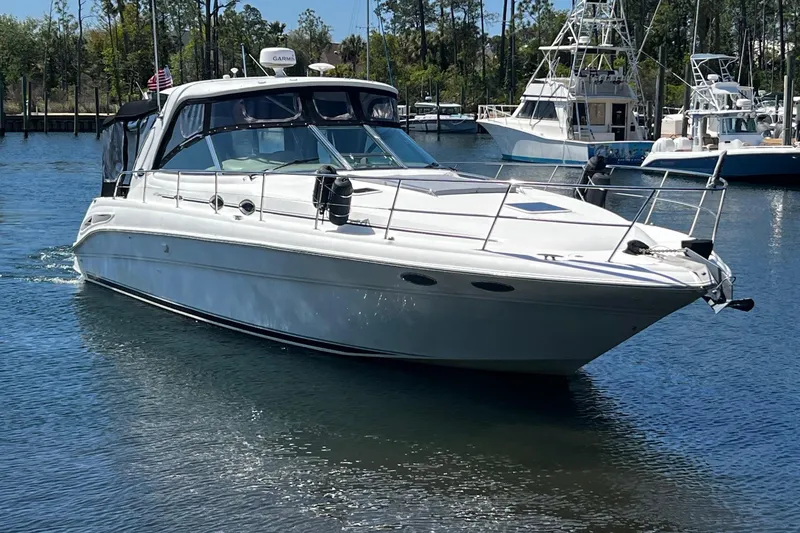 Slide: The Image of 2003 Sea Ray 410 Express Cruiser on calm water, docked with other boats nearby. - 9