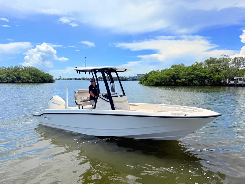 Slide: The Image of A 2027 Boston Whaler 220 Dauntless on calm water, surrounded by green vegetation. - 2