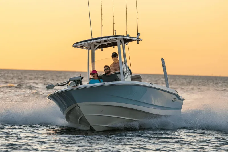 Slide: The Image of A 2027 Boston Whaler 220 Dauntless on the water at sunset with three people on board. - 12