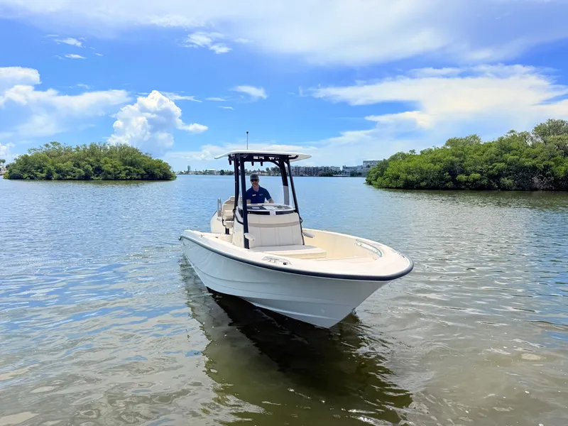 Slide: The Image of A 2027 Boston Whaler 220 Dauntless on calm water, surrounded by green islands. - 3