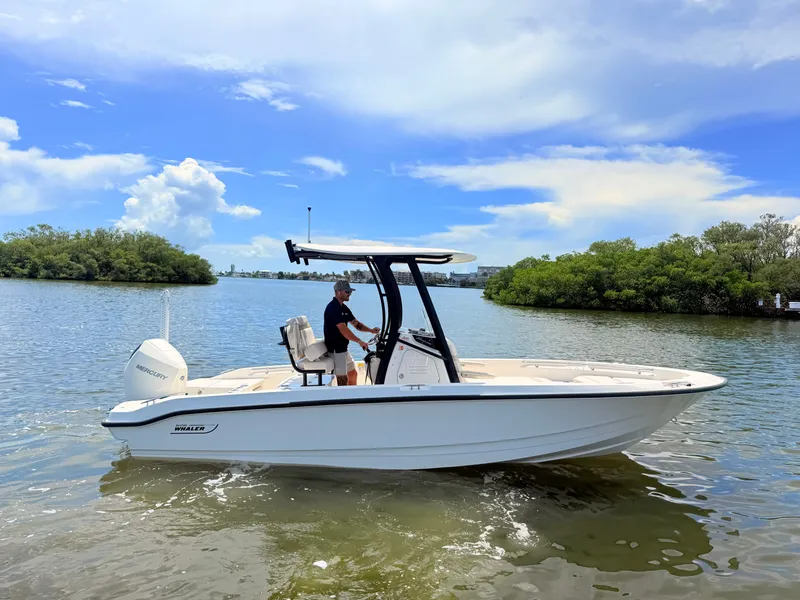 Slide: The Image of A 2027 Boston Whaler 220 Dauntless on calm water with a person at the helm. - 1
