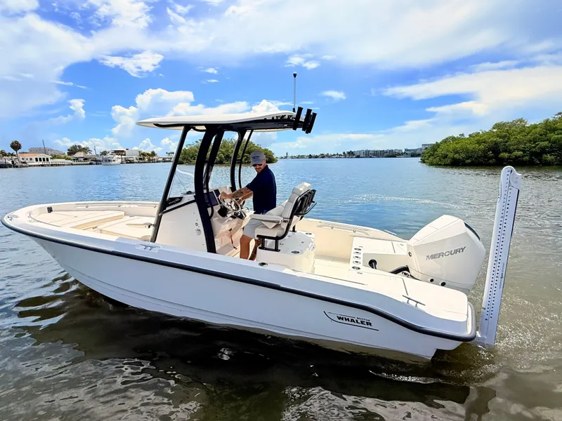 Slide: The Image of A 2027 Boston Whaler 220 Dauntless on calm water. A man is steering the boat. - 10