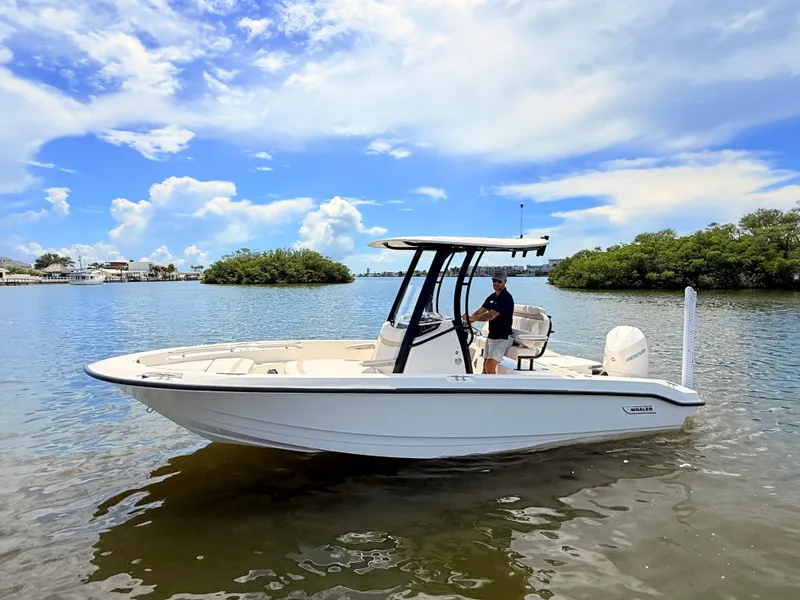 Slide: The Image of A 2027 Boston Whaler 220 Dauntless on calm water with a driver at the helm. - 8