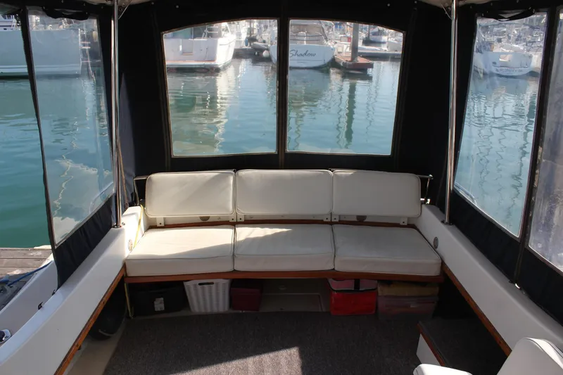 Slide: The Image of Interior view of 1988 Cape Dory 28 Hardtop boat with cushioned seating and marina backdrop. - 10