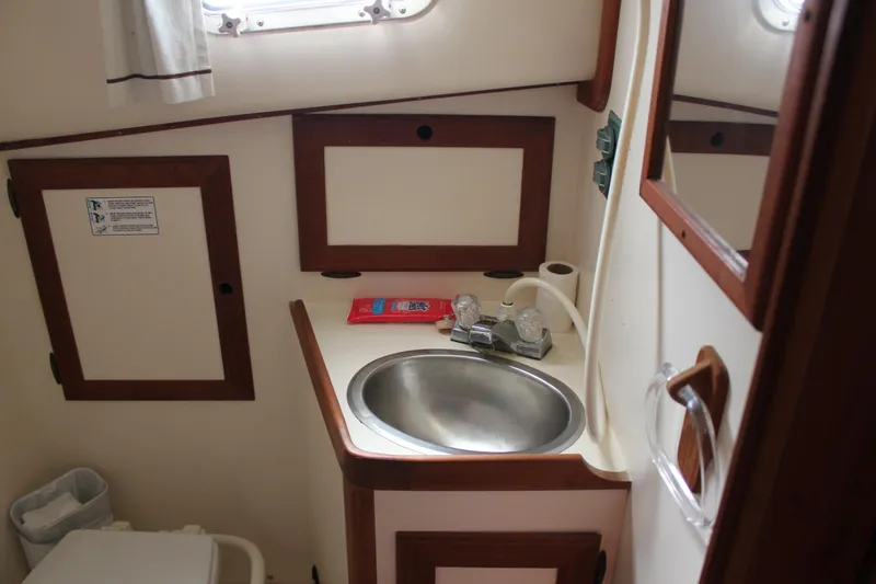 Slide: The Image of 1988 Cape Dory 28 Hardtop boat bathroom with sink, faucet, and storage cabinets. - 23