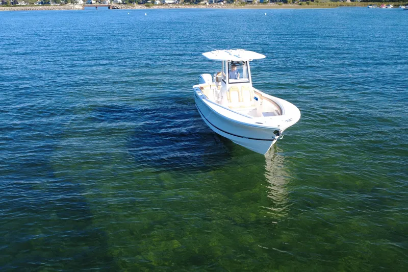 Slide: The Image of 2025 Regulator 25 boat on clear blue water, near shoreline. - 14