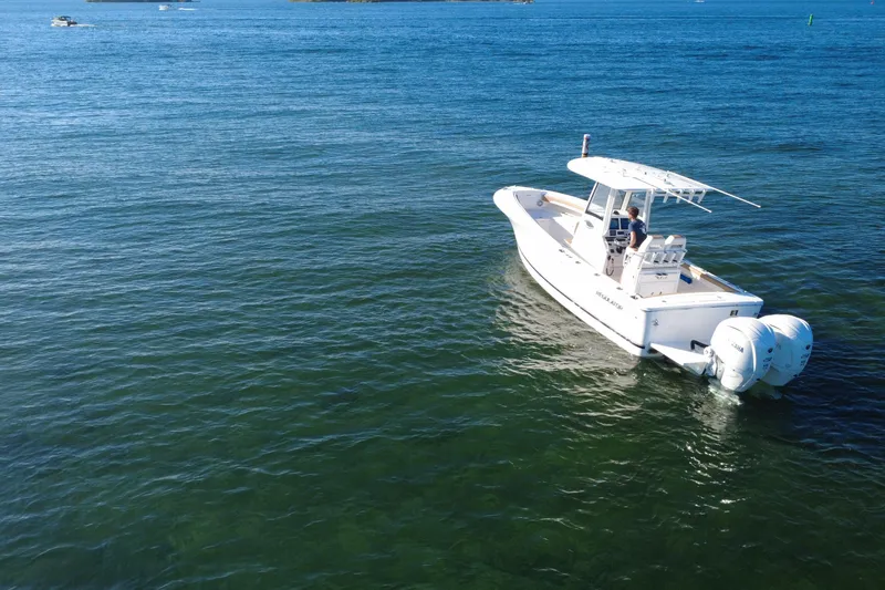 Slide: The Image of 2025 Regulator 25 boat cruising on clear blue water, featuring twin engines. - 16