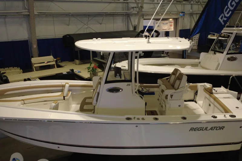 Slide: The Image of 2025 Regulator 25 boat displayed indoors, featuring sleek design and modern seating. - 19