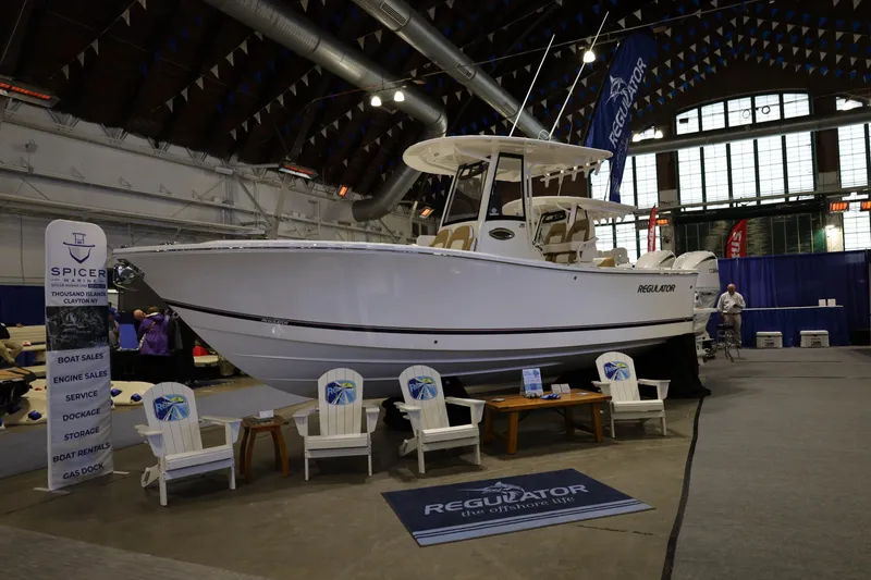 Slide: The Image of 2025 Regulator 25 boat displayed at an indoor boat show with seating area. - 21