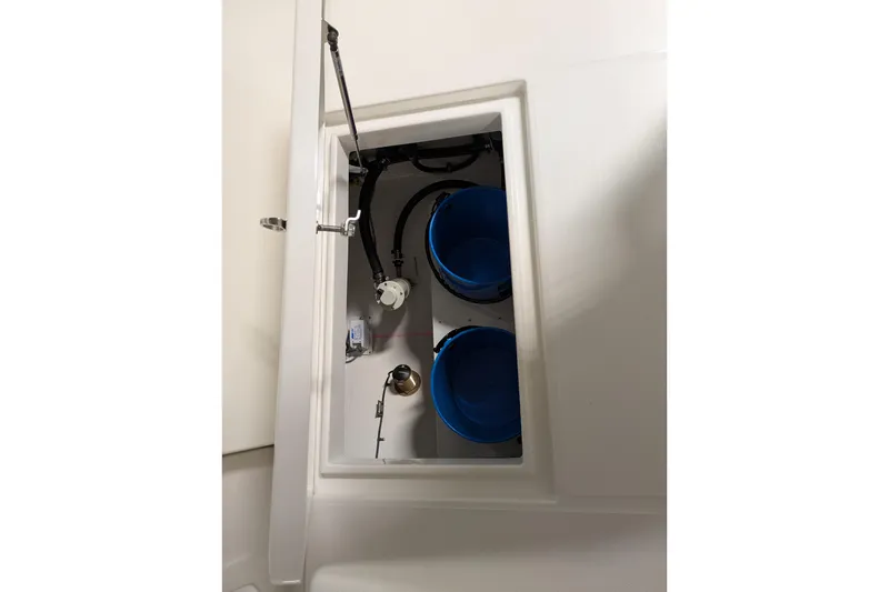 Slide: The Image of 2025 Regulator 25 boat storage compartment with blue buckets and mechanical components. - 29