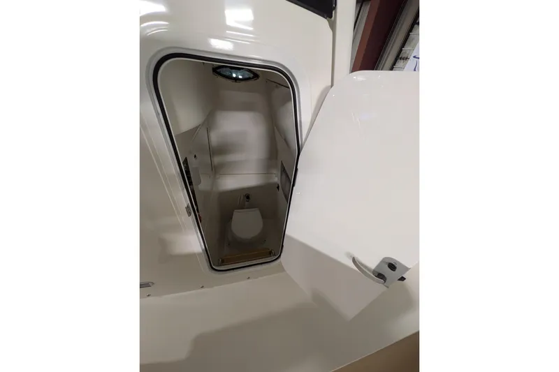 Slide: The Image of 2025 Regulator 25 boat interior with open door revealing compact marine toilet. - 49
