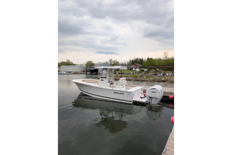Slide: The Image of 2025 Regulator 25 boat docked on calm water with Yamaha engine. - 60
