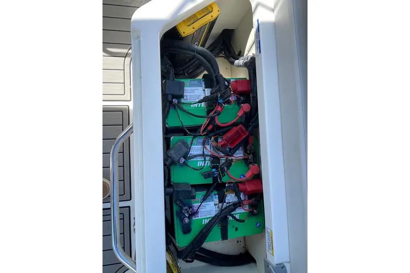 Slide: The Image of 2023 Sea Ray SDX 290 Outboard battery compartment with multiple green batteries and wiring. - 22