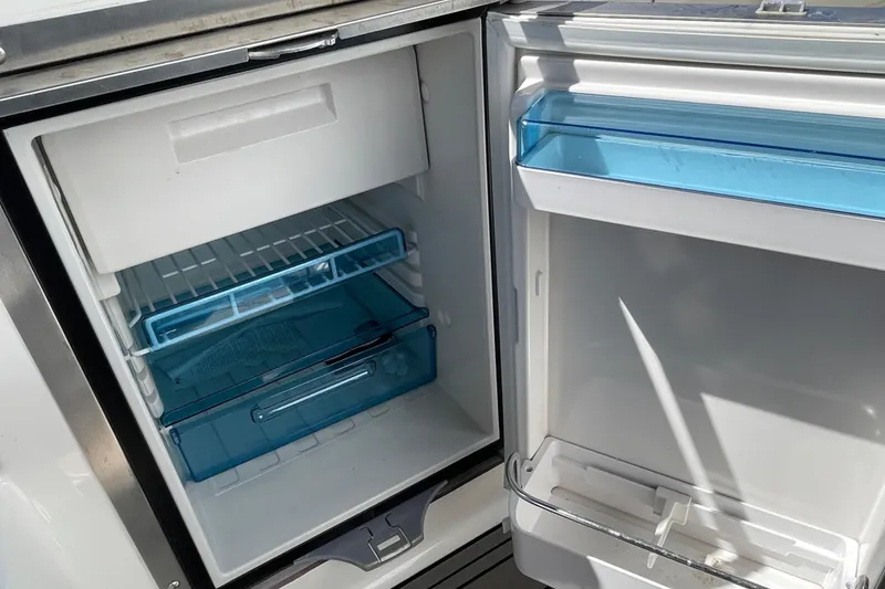 Slide: The Image of Open refrigerator on 2023 Sea Ray SDX 290 Outboard boat, featuring blue storage compartments. - 23