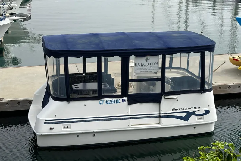 The Image of 2012 ElectraCraft CAT 16 boat docked with blue canopy and clear windows. - 1