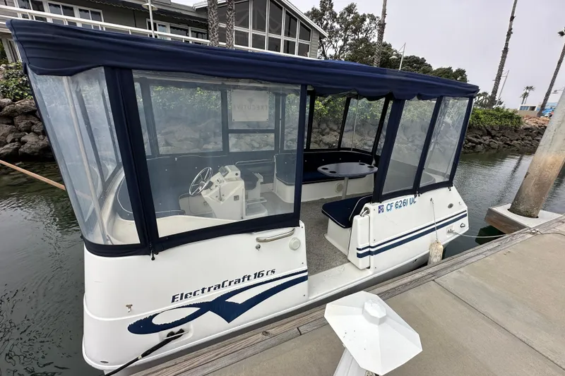 Slide: The Image of 2012 ElectraCraft CAT 16 boat docked, featuring enclosed seating and steering console. - 4
