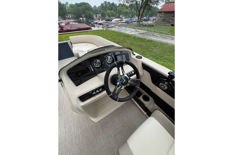 Slide: The Image of 2026 Tahoe Pontoon LTZ CRB dashboard with steering wheel and controls, docked near a lake. - 6