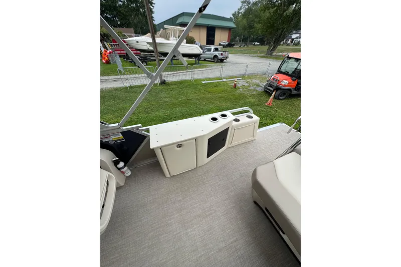 Slide: The Image of 2026 Tahoe Pontoon LTZ CRB interior with seating and storage, parked outdoors. - 8