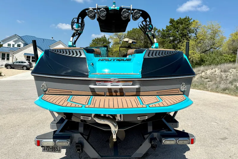 Slide: The Image of 2016 Nautique Super Air Nautique G23 boat, vibrant blue, parked on a sunny driveway. - 13