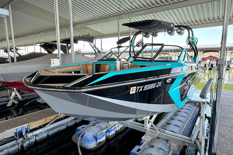 Slide: The Image of 2016 Nautique Super Air Nautique G23 boat in dock, featuring sleek black and turquoise design. - 20