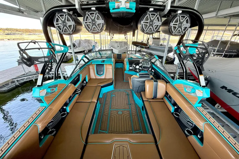 Slide: The Image of 2016 Nautique Super Air Nautique G23 boat interior with teal and brown seating, advanced audio system. - 25