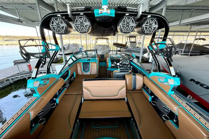Slide: The Image of 2016 Nautique Super Air Nautique G23 interior with brown and teal seating, docked in marina. - 26