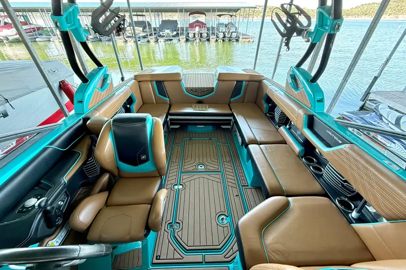 Slide: The Image of 2016 Nautique Super Air Nautique G23 interior with brown and teal seating, docked by the lake. - 28