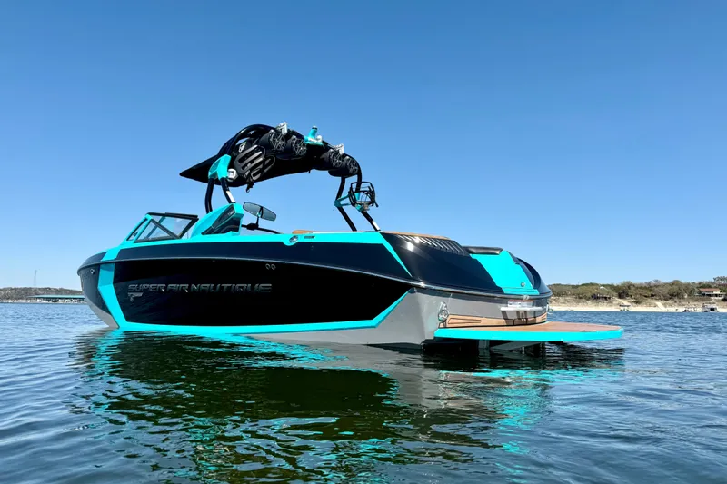 Slide: The Image of 2016 Nautique Super Air Nautique G23 boat on calm water under clear blue sky. - 6