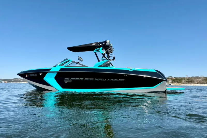 Slide: The Image of 2016 Nautique Super Air Nautique G23 boat on calm water under clear blue sky. - 7