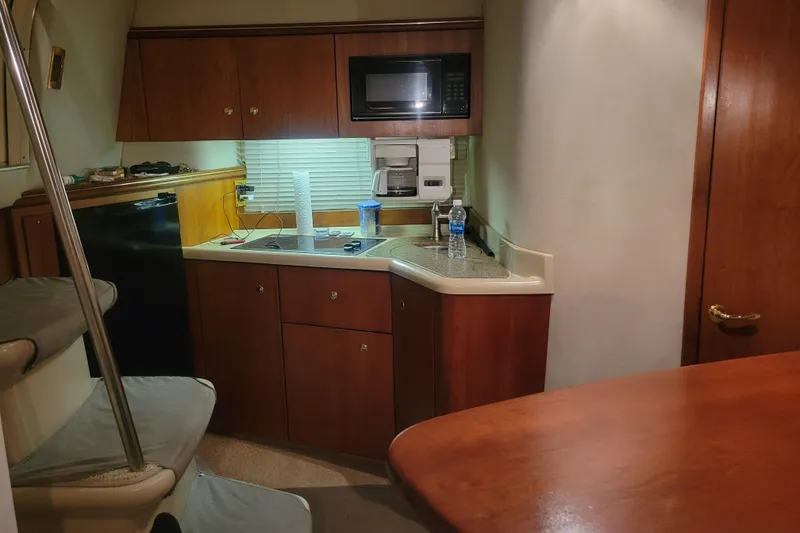 Slide: The Image of Cozy kitchen area in a 2000 Cruisers Yachts 3375 Express, featuring wood cabinetry and modern appliances. - 9