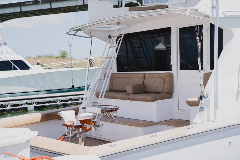 Slide: The Image of 1999 Viking 58 Convertible yacht with cushioned seating and fishing chairs at a marina. - 10