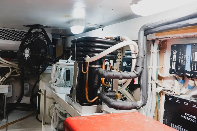 Slide: The Image of Engine room of a 1999 Viking 58 Convertible yacht, featuring mechanical components and wiring. - 107
