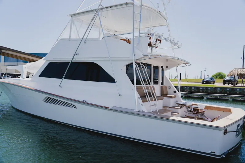 Slide: The Image of 1999 Viking 58 Convertible yacht docked in marina, showcasing sleek design and spacious deck. - 3