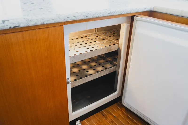 Slide: The Image of Open cabinet with perforated metal shelves on a 1999 Viking 58 Convertible yacht. - 54